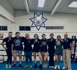 2026 Fresno PAL Lady Boxing graduates with their coaches in the PAL Boxing Gym